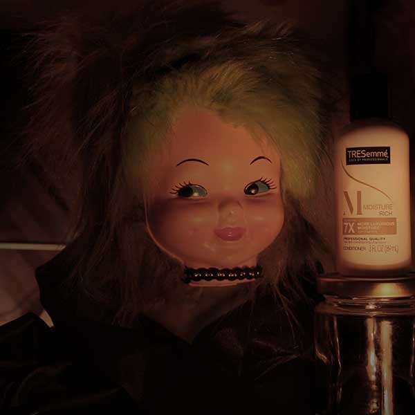 a photgraph of a doll with a shampoo bottle next to it.